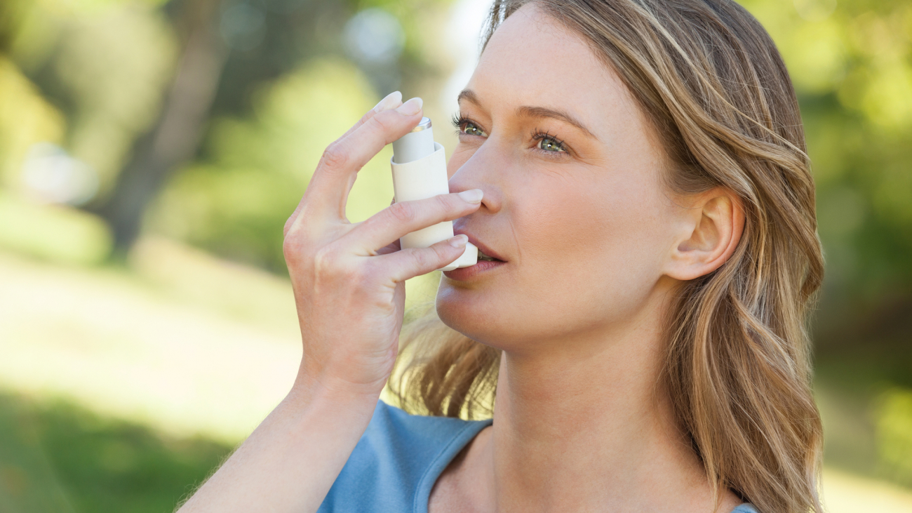 Close-up of a young woman using asthma inhaler in the park